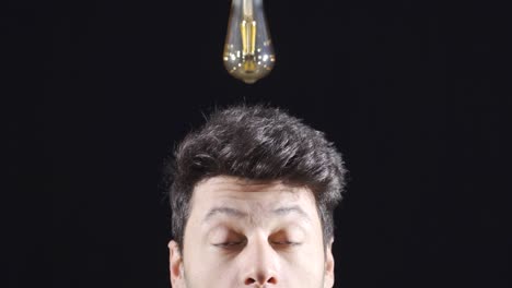 When-the-man-comes-up-with-an-idea,-the-bulb-goes-on-above-his-head.-Brainstorming.